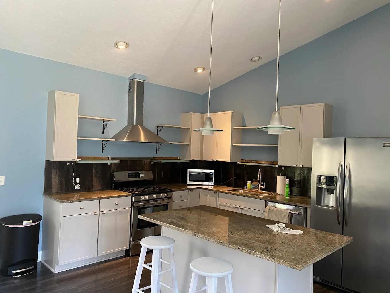 Modern West Michigan kitchen with two-tone cabinets, lighter upper cabinets over darker lower cabinets, and bar stools at the island