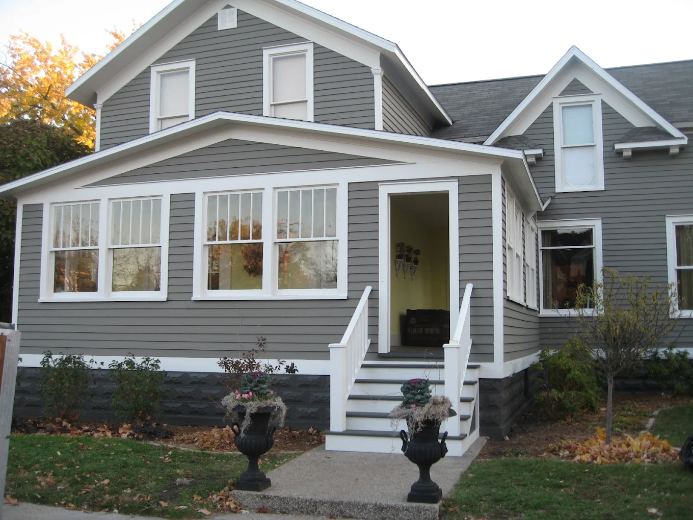 Gray two-story house with a yellow front door and white porch railings