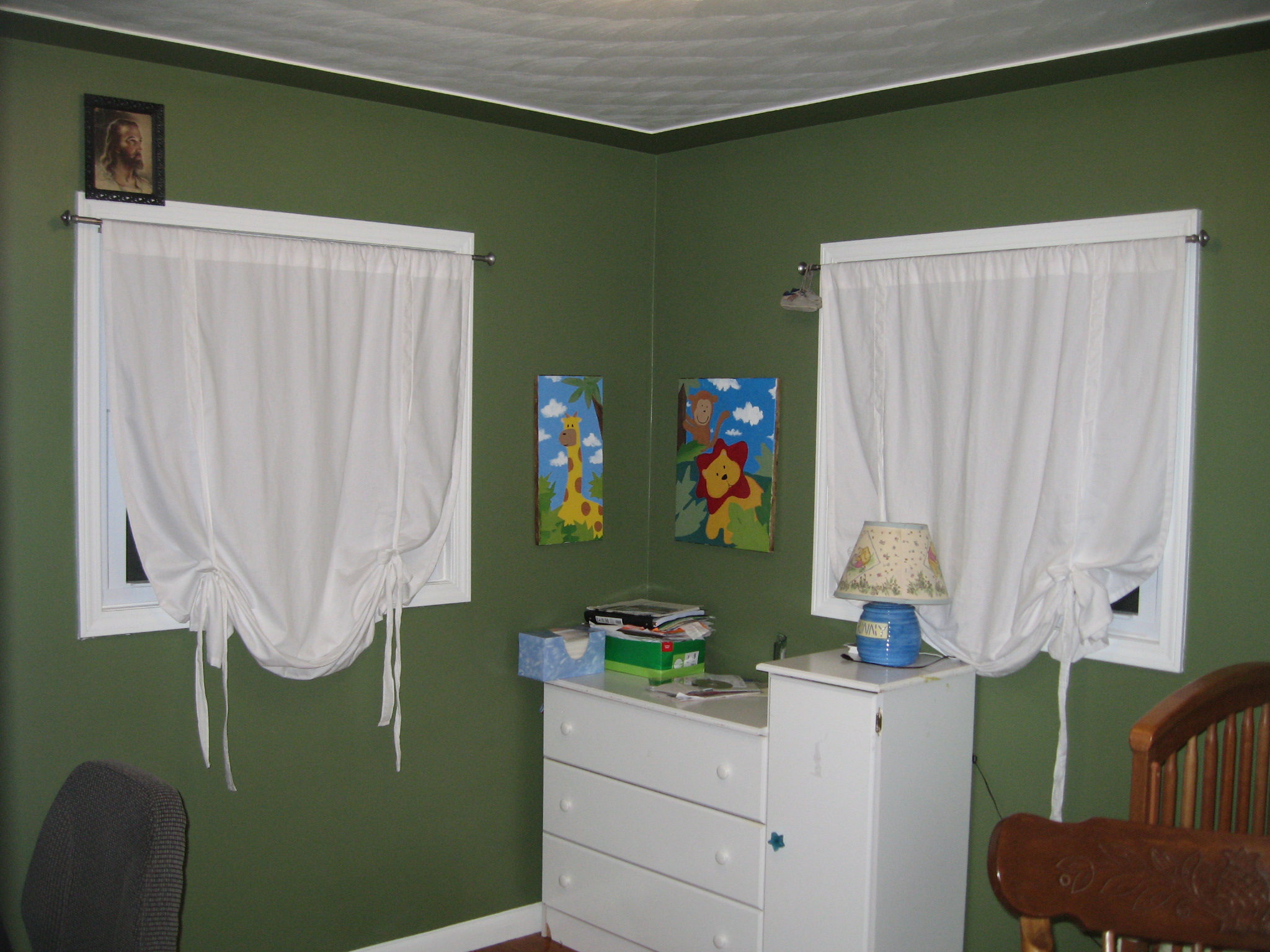 Bedroom with green walls, white sheer curtains and a white dresser beside a lamp, styled for a cozy refresh