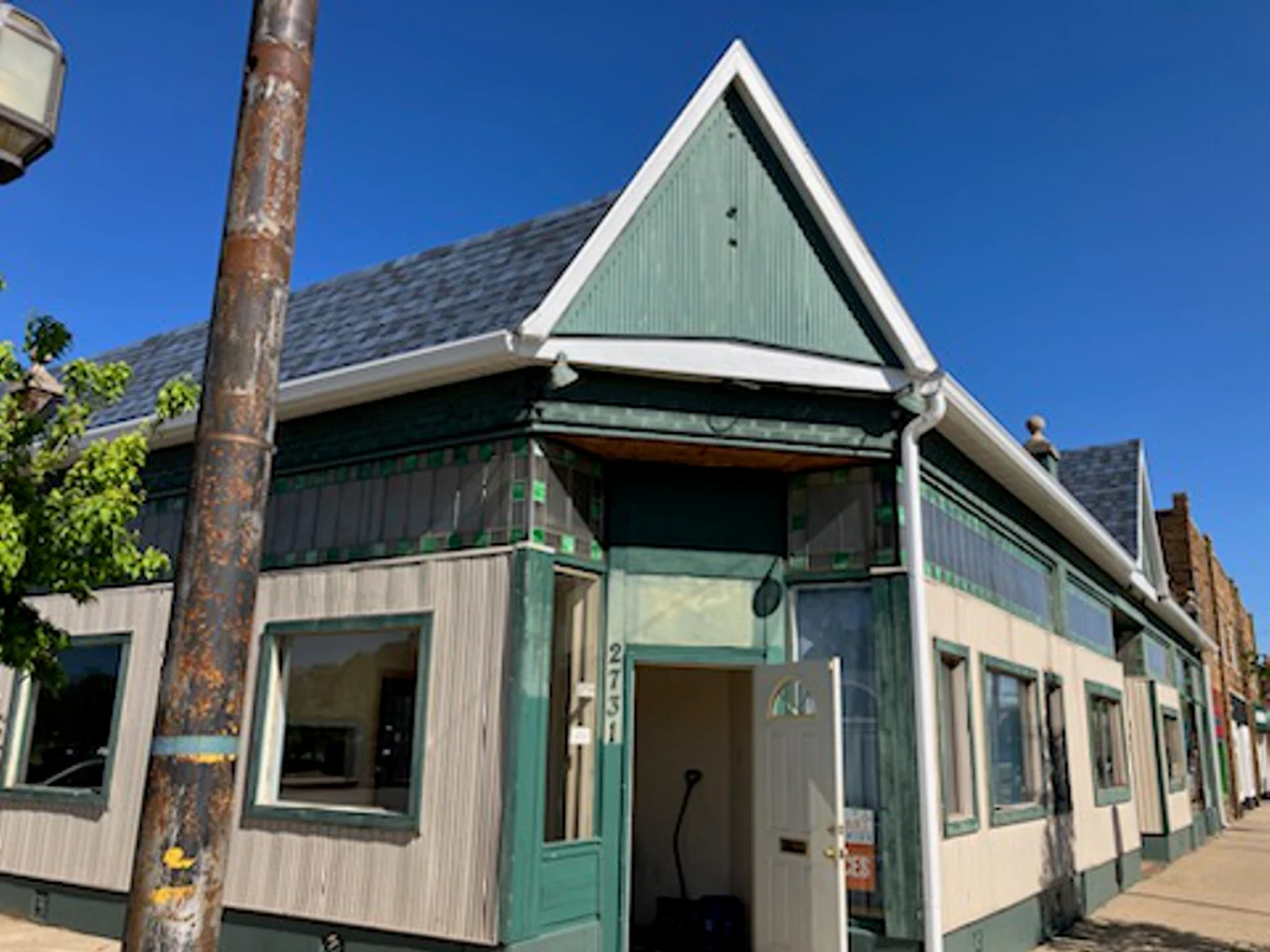 Teal two-story house with dark trim and a gabled roof, beside a utility pole on a Muskegon street