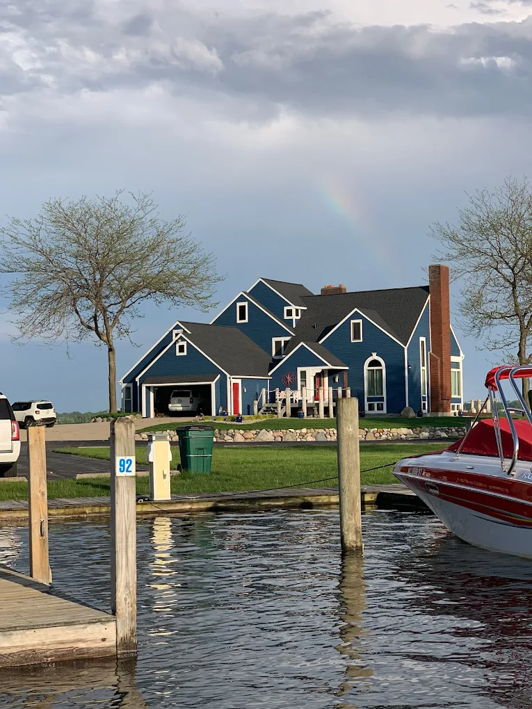 Blue lakefront home with a dock, a moored boat and a rainbow over Lake Michigan in Grand Haven