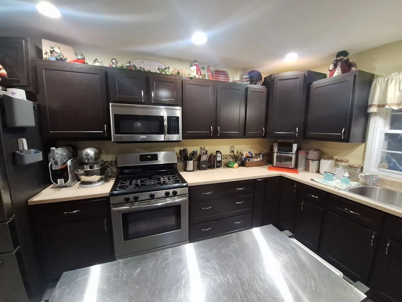 Kitchen with dark cabinets, stainless steel range and light countertops