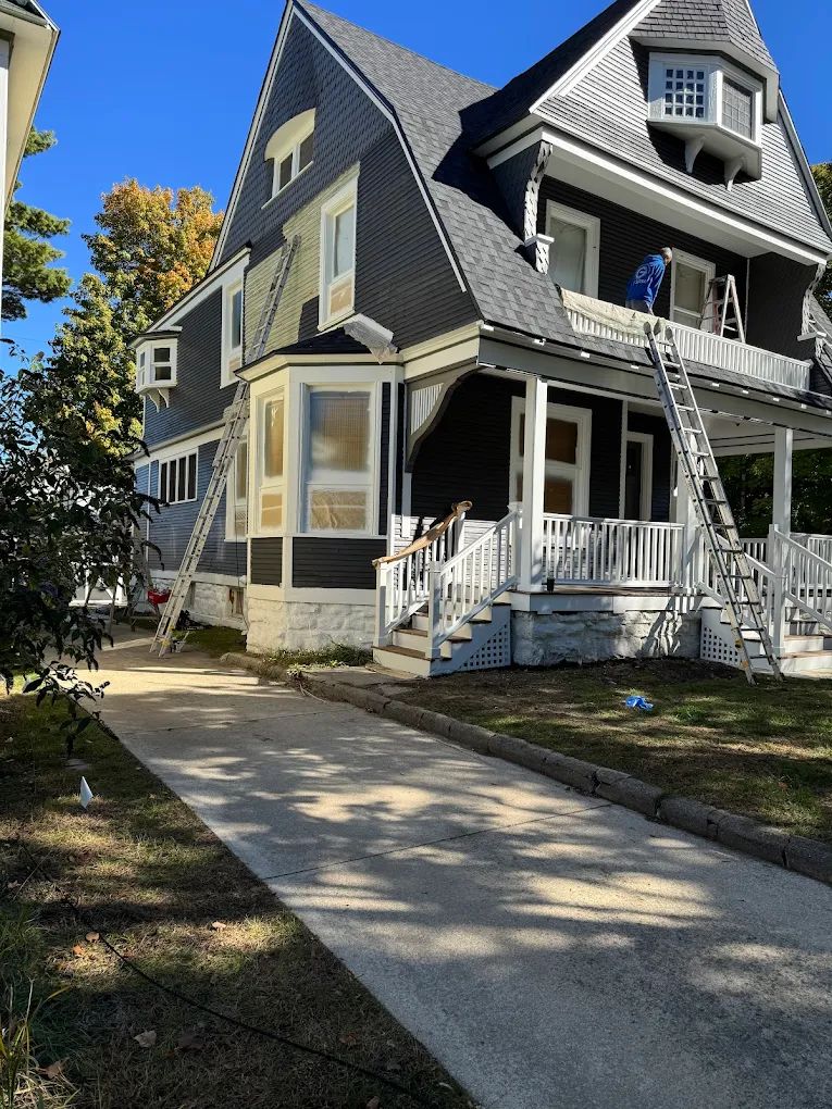 Two-story house with a ladder against the siding, prepared for exterior painting